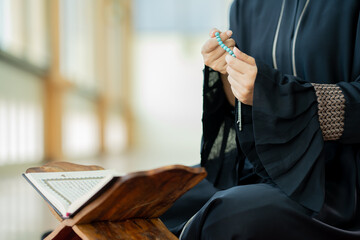 Fototapeta premium The image of an Asian Muslim woman in the Islamic religion in hijab in cream and black color. She was praying in a beautiful mosque out of respect for God.