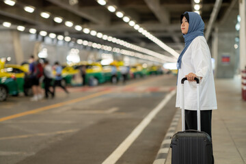 An Asian Muslim wearing a blue hijab is preparing for a vacation and she is at the airport. She's going to call a taxi, Muslim travelers.