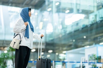 An Asian Muslim wearing a blue hijab is preparing for a vacation and she is at the airport. She is waiting for her friends, Muslim travelers.