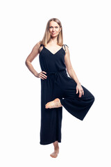 Fototapeta premium Young woman in heron yoga pose. Smiling beauty woman in stylish black clothes. Fitness, health and sports. Isolated on white background. Vertical.