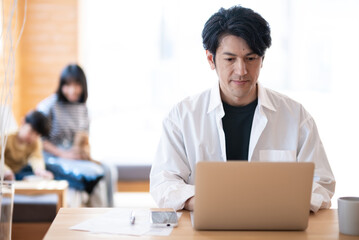 自宅で仕事をする日本人男性とくつろぐ姉弟