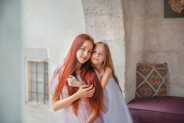 Fototapeta premium Beautiful girls. Mom and daughter. Sisters on vacation. Rest at the hotel. Holidays. Beautiful sisters with long hair. The sisters hug. Vacation. Relax. Cappadocia. Two sisters. Tenderness. Family. 