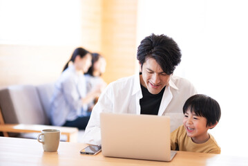 Fototapeta premium パソコンを触る男の子と見守る父
