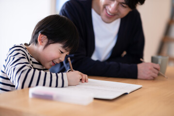 宿題をする男の子と見守る父親