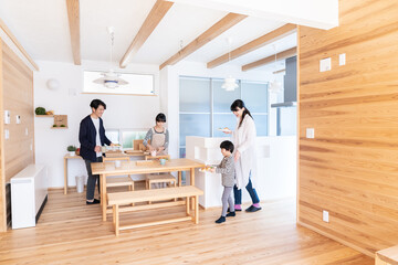 ご飯をテーブルに運ぶ家族 © milatas