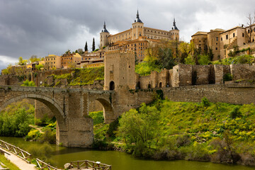 Fototapeta na wymiar Scenic spring cityscape of old town of Toledo with Alcantara bridge and Alcazar fortress, central Spain
