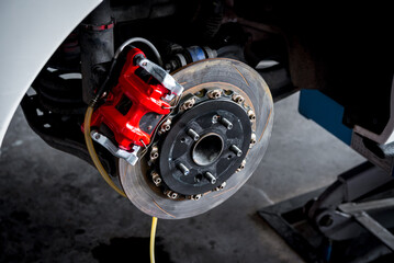 Car mechanic or serviceman disassembly and checking a disc brake and asbestos brake pads for fix and repair problem at car garage or repair shop