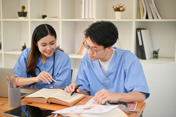 Two medical students are studying and researching medical information at the library together.