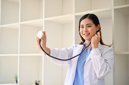 Attractive Asian female doctor in white gown with a stethoscope.