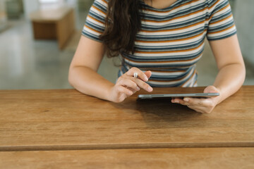 Woman holding a book device reading on e-book on digital tablet device or social media apps online ecommerce.