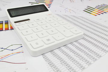 White modern calculator on financial documents and data, wide angle image. Concept of business, calculating, planning and accounting.