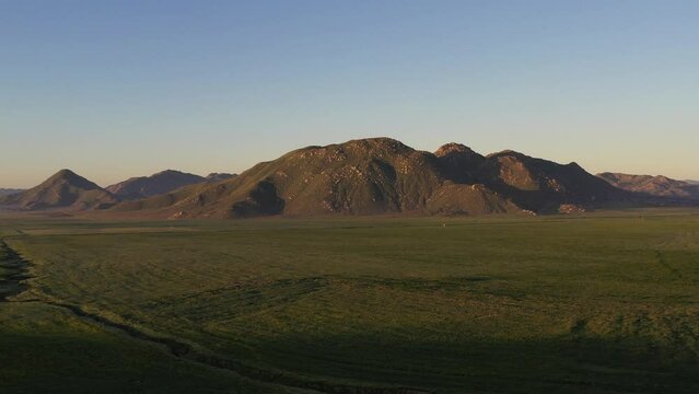 Drone video of  Gilman Springs road with green grass valley and mountains 2 of 4