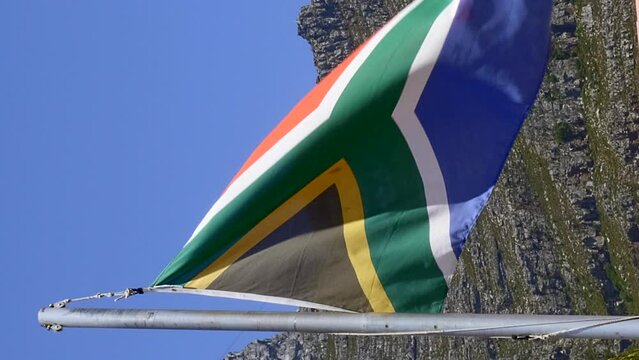 Vertical close up of blowing South African flag, Table Mountain in background.