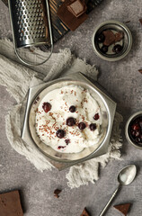 White ice cream sundae with fresh berries and chocolate chips in a vintage vase on the table with appliances and products for making a cooling dessert.
