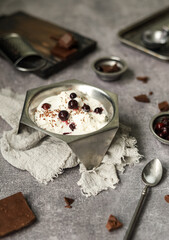 Creamy ice cream sundae with fresh berries and chocolate chips in a vintage vase on the table with appliances and products for making a cooling dessert.