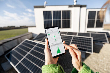 Woman monitors energy production from the solar power plant with mobile phone. Close-up view on phone screen with running program. Concept of remote control of solar energy production - 593463655