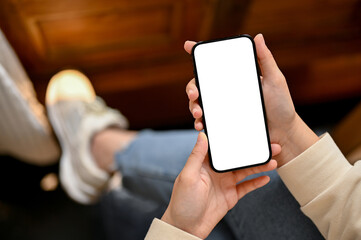 Plakat Top view of a woman in casual clothes using her smartphone while chilling in a coffee shop