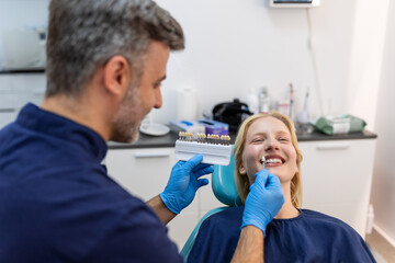 Image of satisfied young woman sitting in dental chair at medical center while professional doctor...