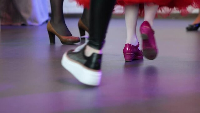 Children's feet in red shoes are dancing among adults