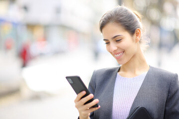 Happy executive using cell phone in the street