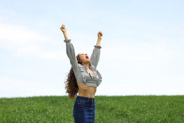 Excited woman raising arms in a field
