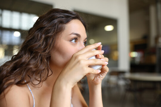 Distracted woman drinking coffee from cup in a restaurant