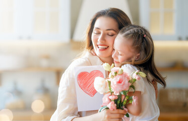 Daughters giving mother bouquet of flowers. - obrazy, fototapety, plakaty