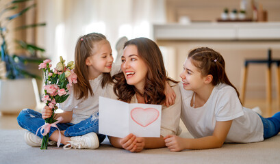 Daughters giving mother bouquet of flowers.