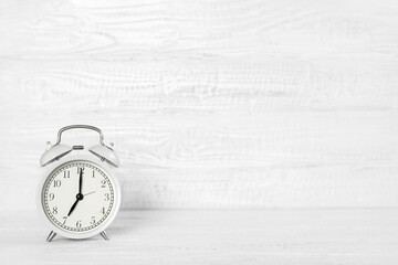 Front view white desk with alarm clock, coffee mug and copy space. Morning background banner with free space for text. Minimalistic concept, workspace, time to work. Blank workplace. Office mock-up