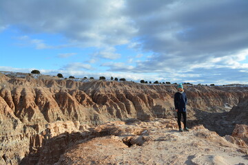 woman in the Cathedral Gorge State Park on a cold day in December, located in a long, narrow valley in southeastern Nevada, where erosion has carved patterns in bentonite clay