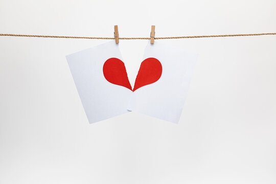 Broken love heart hanging on a rope on a white background