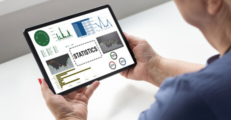 Laptop on wooden table showing charts and graph with white cement wall, Analysis Business Accounting, Statistics Concept.