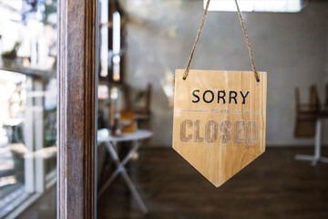 Sign text hangs on the entrance door of the shop, restaurant, cafe. That reads "Sorry, we're closed". Business concept