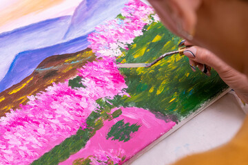 A woman artist is working on a painting with a palette knife.