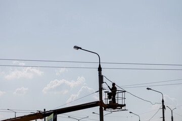 silhouette of a worker painting a lamppost