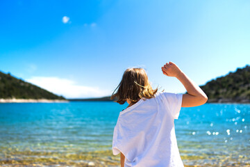 Blondes Kind spielt am Strand in Kroatien im Urlaub und freut sich auf das Wasser