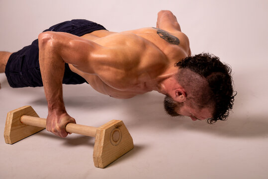 A young muscular man is doing push-ups on parapets.