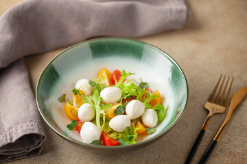 Salad with lettuce, mozzarella and tomatoes in a plate on the table. Caprese salad.