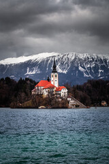 Bled Slovenia - Beautiful view of Lake Bled (Blejsko Jezero) with Pilgrimage Church of the Assumption of Maria on Bled Island, Bled Castle and Julian Alps at background at winter time with dark clouds