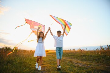 Children launch a kite in the field at sunset