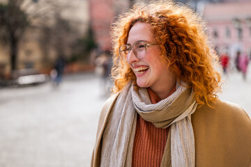 Natural portrait of smiling caucasian ginger woman with freckles and curly hair.