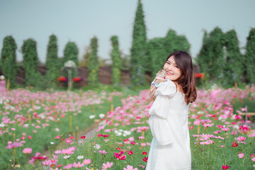 Portrait of young beautiful Asia model woman enjoy with pet prairie dog in spring or summer pink cosmos flower field blooming in garden. girl and animal on sunny.