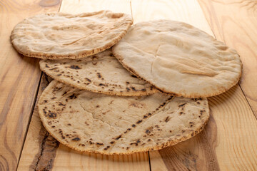 Four pita bread, close-up, on a wooden table.