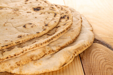 Four fresh pita bread, close-up, on a wooden table.