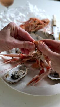 Woman cleaning prawns above table full of fresh seafood with oyster and shrimp from fish market