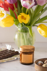 Soy aroma candle in a glass jar with a wooden lid. Copy space label. Beauty and spa. Aromatherapy at home. Scented candles set. Minimalism aesthetic background. Cozy romance mood. Spring tulips.