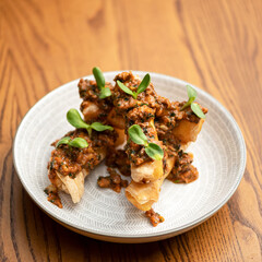 Cold appetizer with vegetable sauce and microgreens. Fried pita bread with spicy sauce. White plate. View from above. Plate on wooden board. Wooden background. Copy space. 