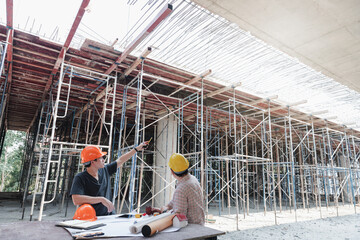 Construction concept of Engineer and Architect working with construction model and blueprint at construction site, Engineer and Architect discussing construction plan at building site