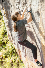 Obraz na płótnie Canvas young active teen girl doing outdoor rock climbing bouldering on natural cliff