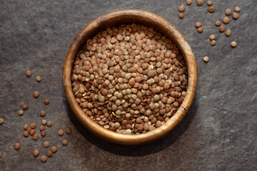 raw lentils in a wooden bowl close up on an old table